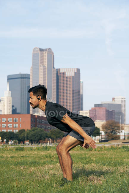 Athlète hispanique masculin en tenue active sautant avec les bras surtendus avec le centre-ville de Dallas, Texas, USA — Photo de stock