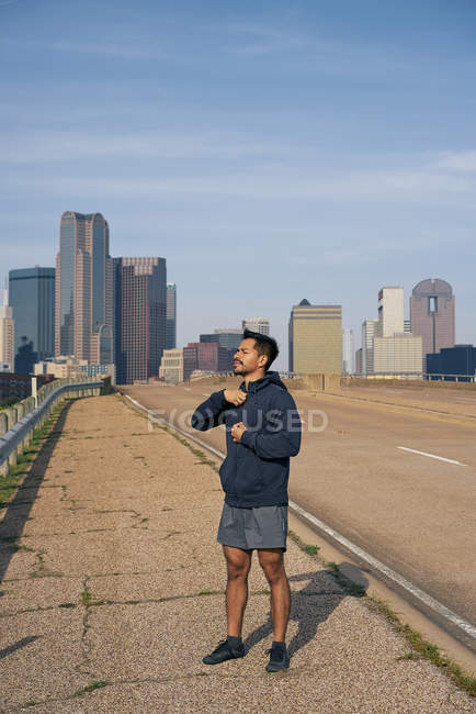 Jeune athlète hispanique avec les yeux fermés debout sur le bord de la route dans le centre-ville de Dallas, Texas — Photo de stock