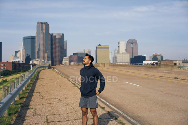 Jeune athlète hispanique avec les yeux fermés debout sur le bord de la route dans le centre-ville de Dallas, Texas — Photo de stock