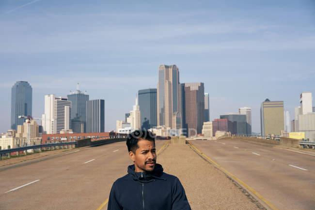 Young Hispanic male athlete walking on side of road in downtown Dallas, Texas — Stock Photo