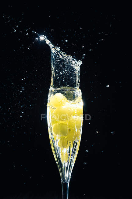Uve che cadono in vetro di champagne — Foto stock
