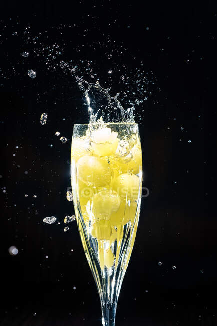 Raisins tombant dans une coupe de champagne — Photo de stock