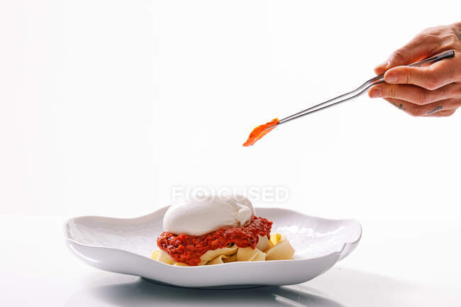 Faceless chef decorating pasta using tweezers — Stock Photo