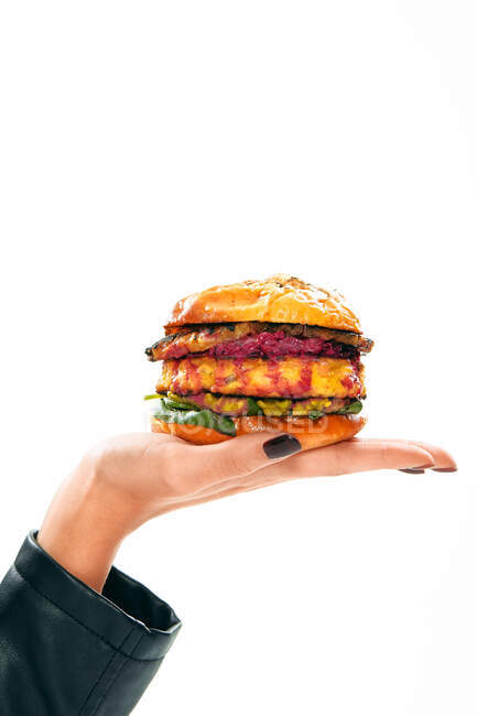 Hand einer anonymen Dame mit doppeltem Burger im Studio — Stockfoto
