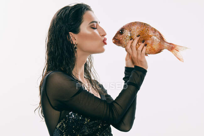 Pretty lady kissing round fish — Stock Photo