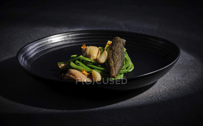 Изысканное мясо с чесночными овощами подается на широком черном блюде — стоковое фото