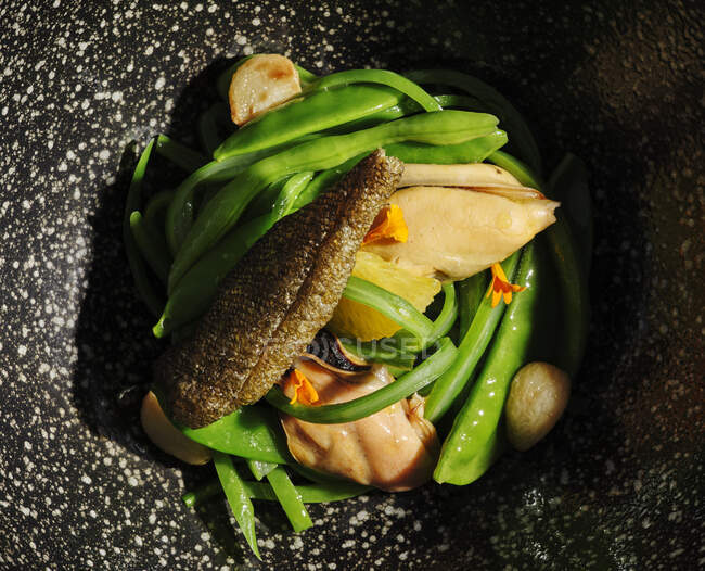 Carne exquisita con verduras de ajo servidas en un amplio plato negro - foto de stock