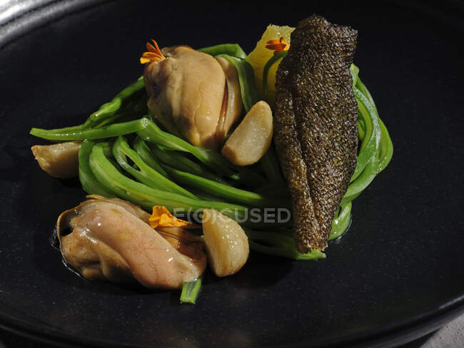 Carne squisita con verdure all'aglio servita su ampio piatto nero — Foto stock