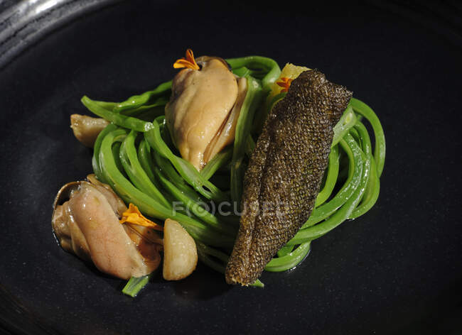 Exquisite meat with garlic vegetables served on wide black dish — Stock Photo