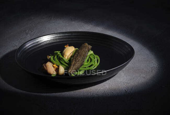 Exquisite meat with garlic vegetables served on wide black dish — Stock Photo