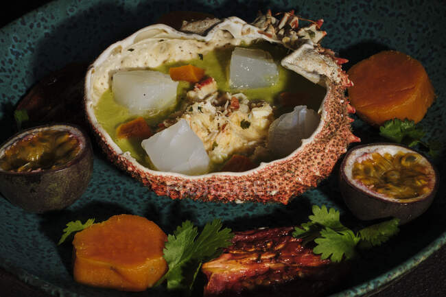 Delicioso ceviche servido en cáscara de cangrejo araña con carne de artrópodo y frutas en el plato en el restaurante - foto de stock