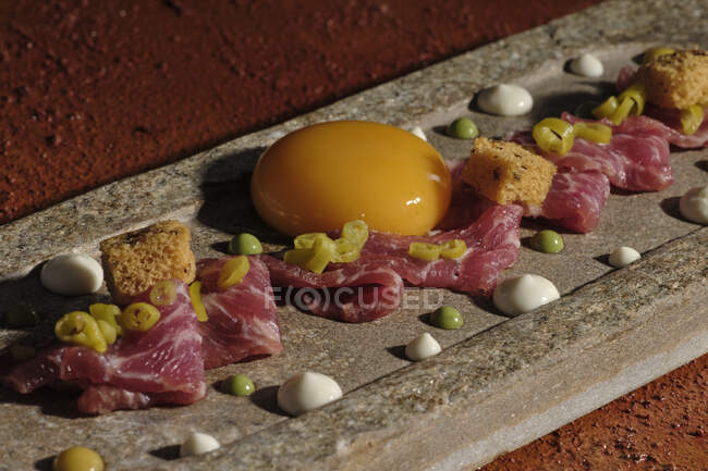 Vista superior de raspas com carne e gema de ovo único dispostos em mergulho no raio de sol — Fotografia de Stock