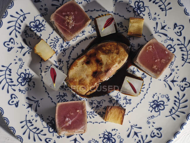 Зверху тарілка з сирими кубиками тунця з овочами, які вишукано подаються на декоративній тарілці — стокове фото