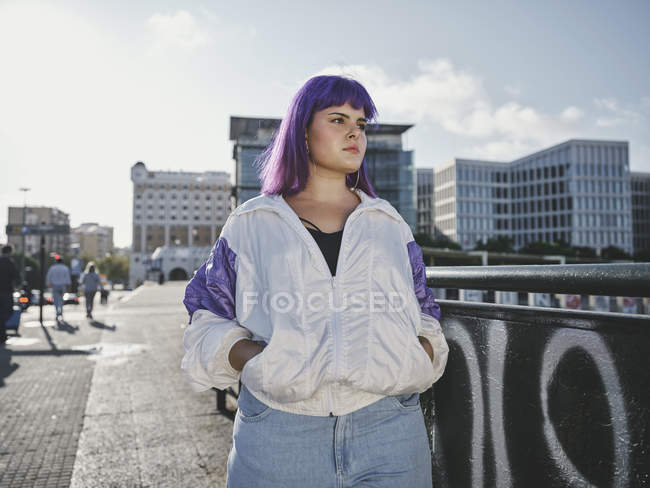 Elegante donna con acconciatura viola in abbigliamento alla moda in posa in ponte urbano in città — Foto stock