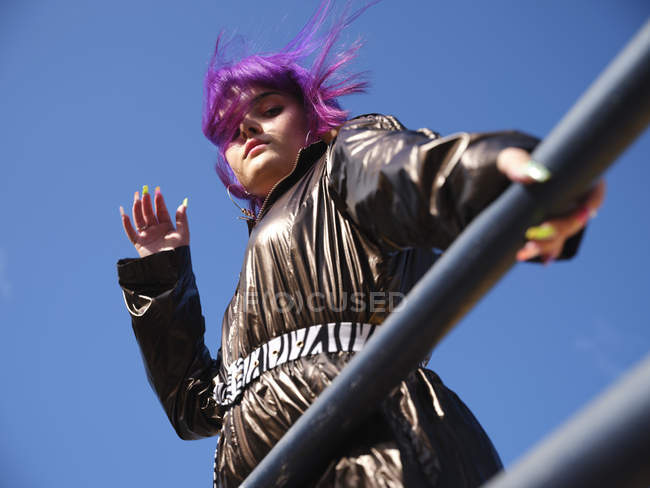 Знизу стильна жінка з фіолетовою зачіскою дивиться в камеру з міської точки зору — стокове фото