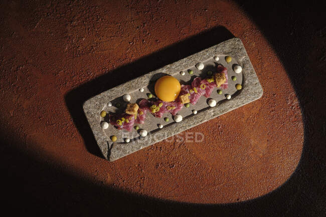 Top view of zest with meat and single egg yolk arranged on plunk in sunbeam — Stock Photo
