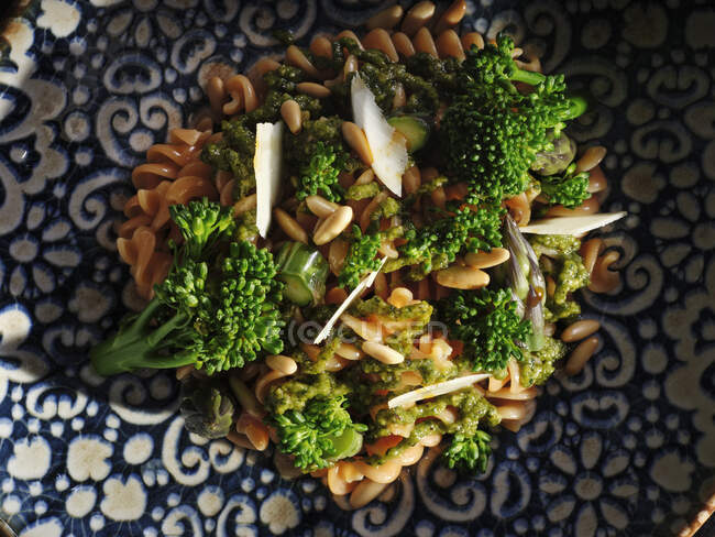 Piatto di pasta con broccoli e pinoli guarnito con formaggio a fette sottili in tavola — Foto stock