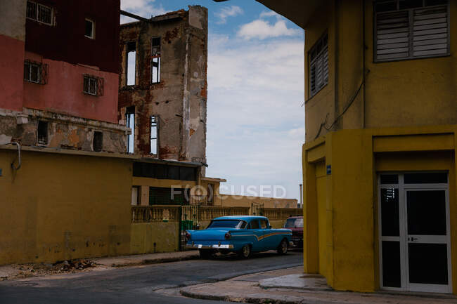 Pequena rua com carro vintage na beira da estrada entre edifícios históricos coloridos com bares em janelas em Cuba — Fotografia de Stock