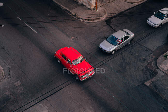 D'en haut de l'intersection de la route asphaltée avec voiture vintage rouge parmi les transports contemporains au milieu de Cuba — Photo de stock