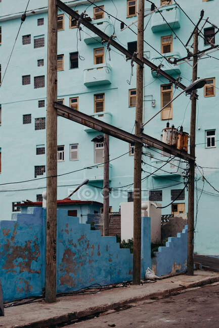 Carretera de asfalto vacía a lo largo de postes articulados de valla balanceada azul y edificio residencial azul en Cuba - foto de stock