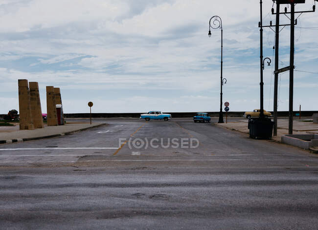 Estrada de asfalto cruzamento com carros antigos azuis entre os transportes contemporâneos no meio de Cuba — Fotografia de Stock