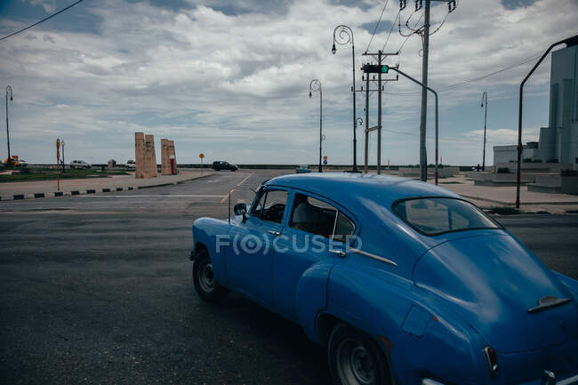 Asphaltierte Straßenkreuzung mit blauem Oldtimer inmitten zeitgenössischer Transporte in Kuba — Stockfoto