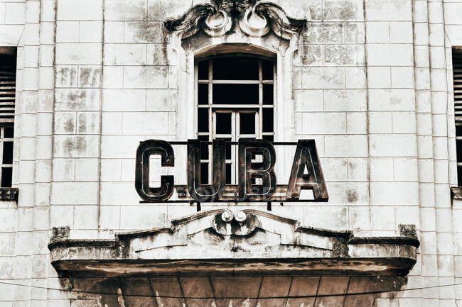 D'en bas de vieux bâtiment à bascule dans un design élégant avec de grandes fenêtres et signe Cuba à l'entrée — Photo de stock