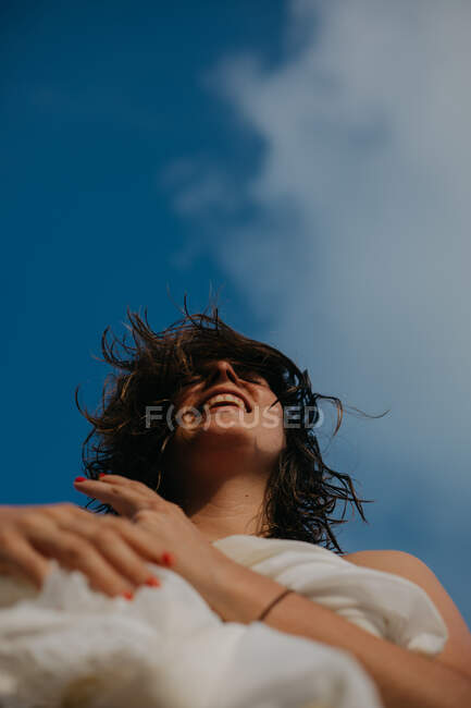Dal basso di allegra giovane donna con i capelli bagnati rilassarsi sulla spiaggia di sabbia nella giornata di sole — Foto stock