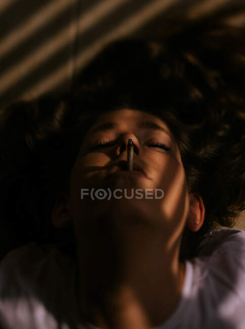 Жінка лежить з закритими очима курить сигарету — стокове фото