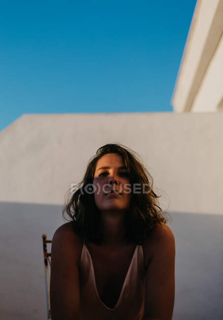 Peaceful happy woman standing with closed eyes on fence of balcony with sunset on blurred background — Stock Photo