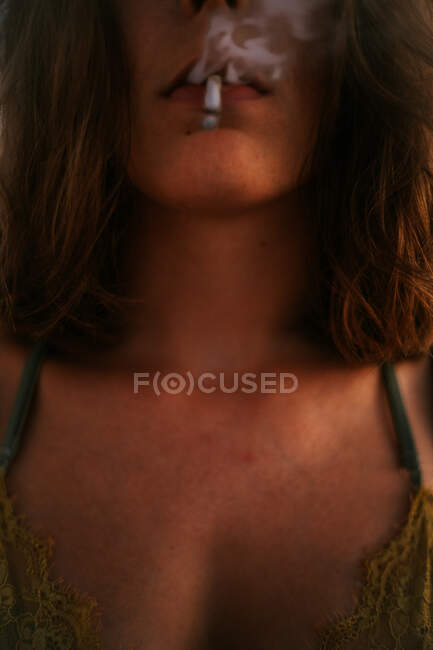 Dal basso donna anonima ritagliata con sigaretta in bocca — Foto stock