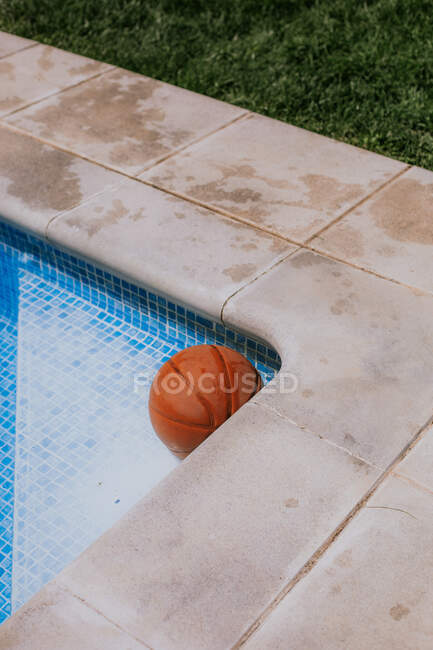 Du dessus du ballon de basket dans le coin sur la piscine en terrasse de la maison avec herbe verte — Photo de stock