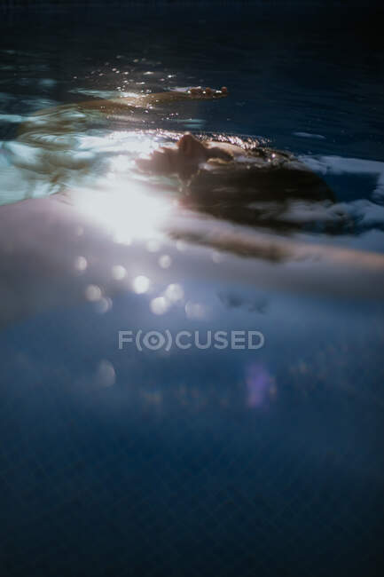 Vista lateral de la cara sobre la superficie del agua de la mujer tranquila en reposo con los ojos cerrados en la piscina en el día de verano soleado - foto de stock