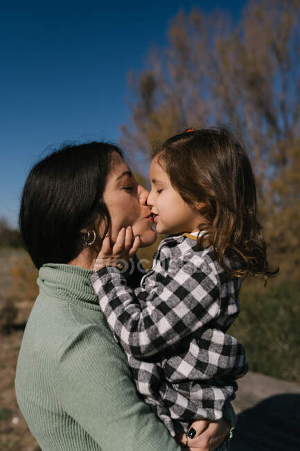 Madre besando y abrazando hija - foto de stock