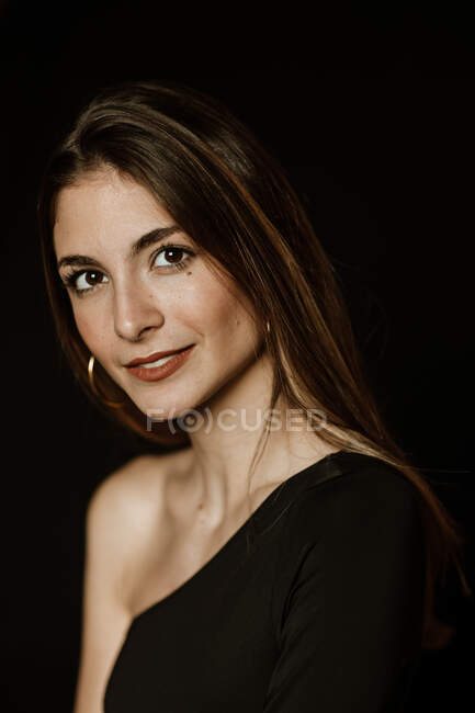 Sensual gorgeous woman in dark dress looking at camera — Stock Photo