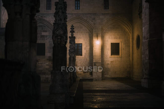 Clôture en pierre avec croix située dans la cour faiblement éclairée de la cathédrale âgée à la nuit noire à Burgos, Espagne — Photo de stock