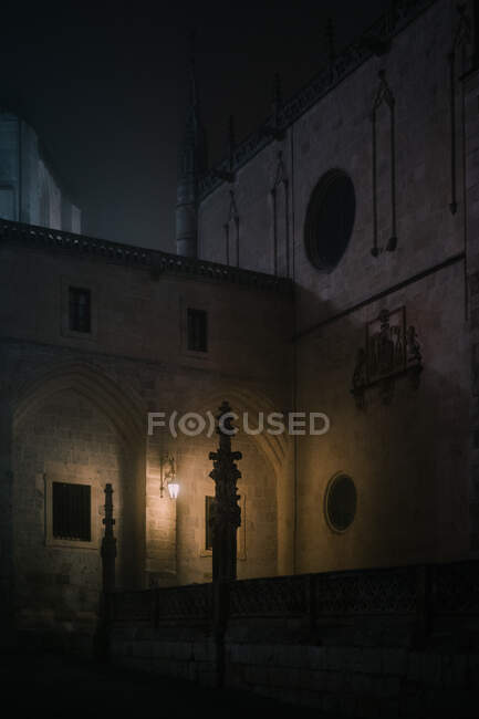 Stone fence with crosses located in dimly illuminated courtyard of aged cathedral at dark night in Burgos, Spain — Stock Photo