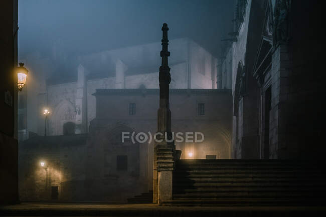 Clôture en pierre illuminée autour de l'ancien bâtiment de la cathédrale lors d'une nuit sombre et brumeuse à Burgos, Espagne — Photo de stock