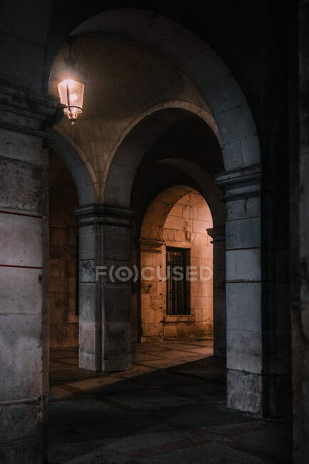 Старомодный фонарь, освещающий потрепанные арки древнего собора ночью в Бургосе, Испания — стоковое фото