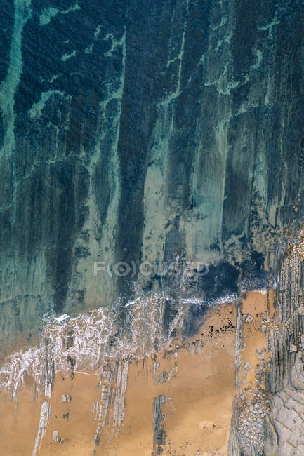 Desde arriba sereno paisaje de olas turquesas lavando playa de arena tranquila en Pielagos, Cantabria, Santander, España - foto de stock