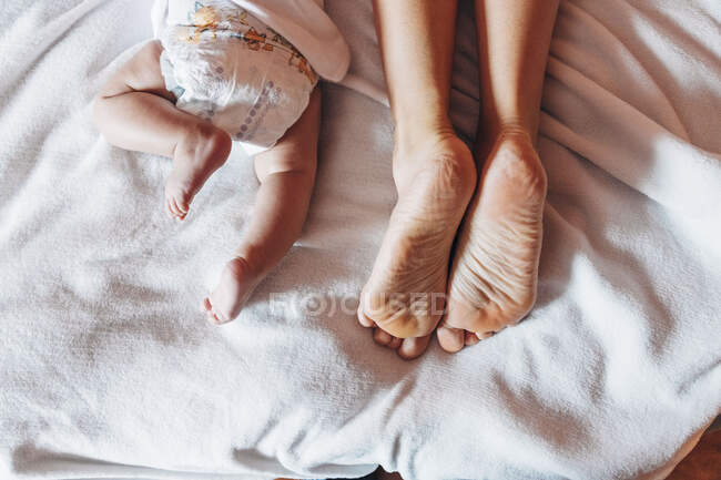 Вид зверху на врожай новонародженої дитини в підгузник лежить на ліжку з матір'ю в будинку — стокове фото