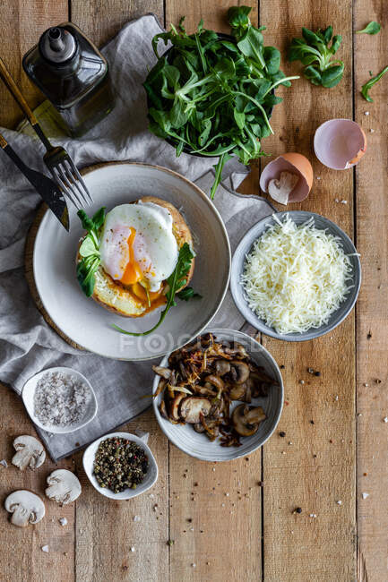 Vista dall'alto uovo fritto su patata su tavolo di legno con funghi fritti formaggio grattugiato ed erbe aromatiche — Foto stock