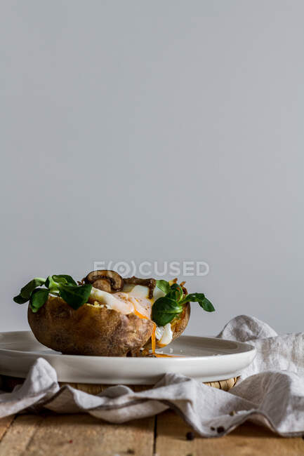 Fried egg on potato on wooden table with fried mushrooms grated cheese and herbs — Stock Photo