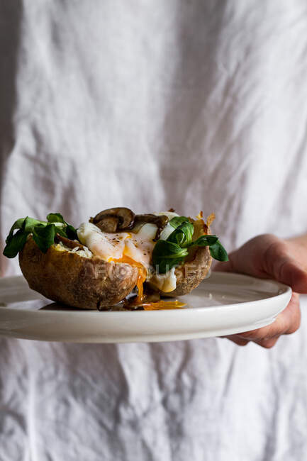 З верху білої керамічної чаші з смачними яєчними грибами в картоплі на руках. — стокове фото