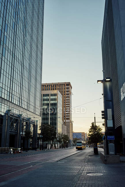 Empty carriageway and sidewalk between modern skyscrapers with blue sky on background at dusk — Stock Photo