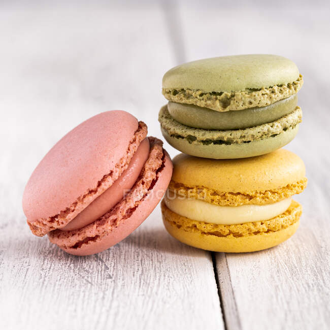 Colorful tasty macaroons stacked in pile against wooden white surface — Stock Photo