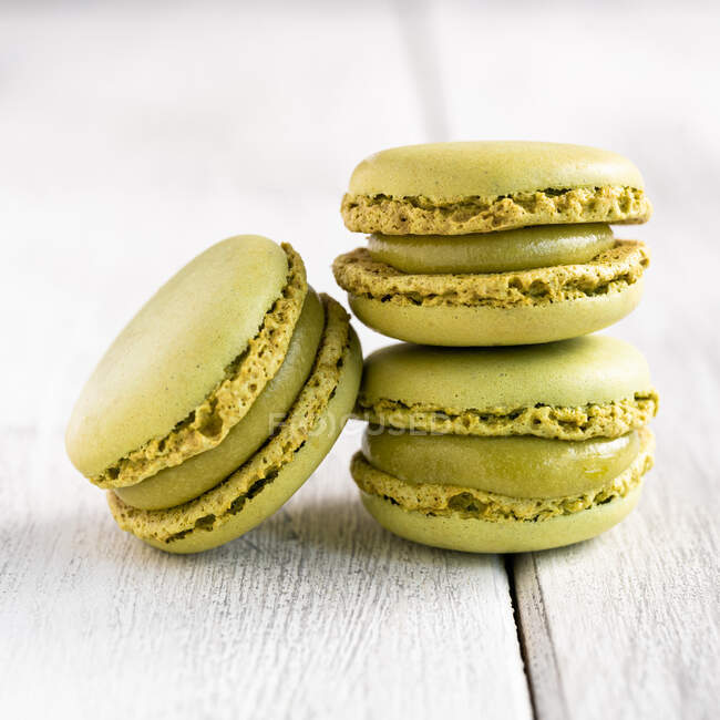 Green tasty macaroons stacked in pile against wooden white surface — Stock Photo