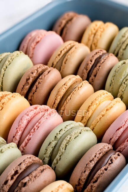 Colorful tasty macaroons displayed inside blue container — Stock Photo