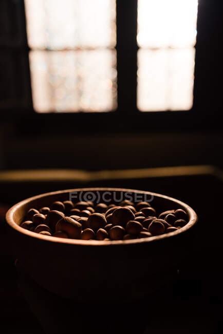 Коричневая деревянная чаша, полная вкусного свежего фундука на черном фоне — стоковое фото