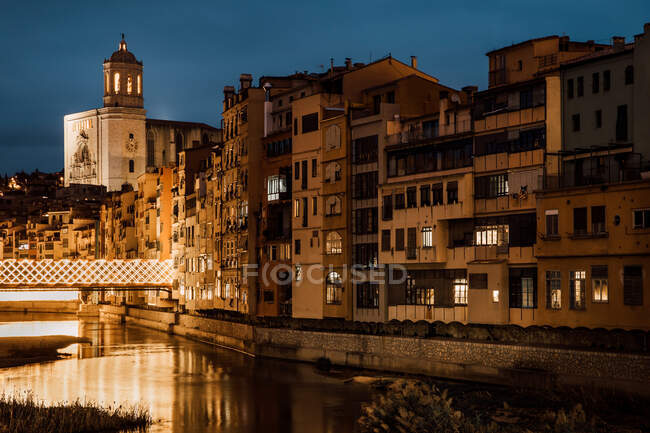 Affascinante paesaggio di fiume che scorre lungo la chiesa e le case in serata a Girona, Catalogna, Spagna — Foto stock